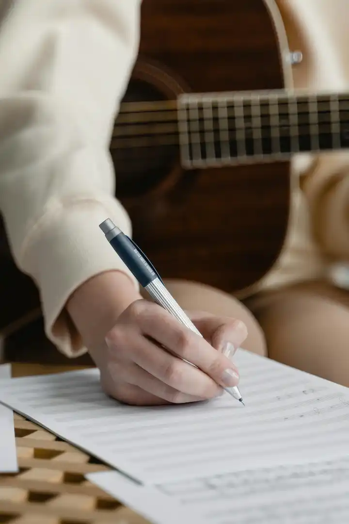Újrakezdőknek szolfézs oktatás - egy felnőtt kottázik gitárral a kezében